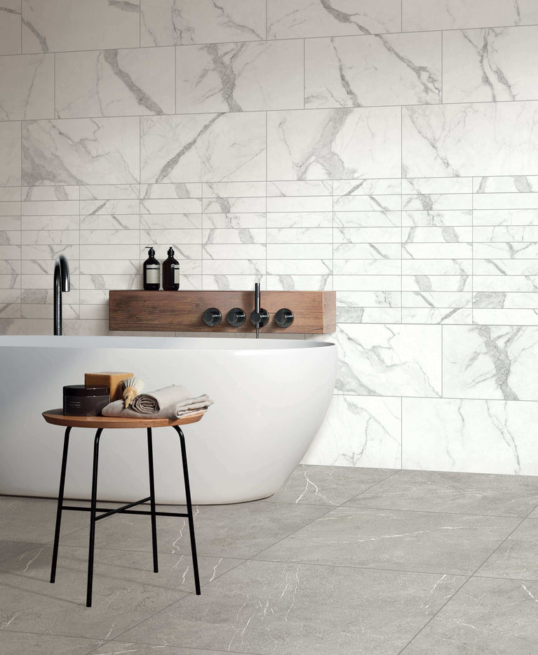Salle de bain moderne avec carrelage en marbre blanc Céramique Marble Stone Bianco, baignoire autoportante, tabouret en bois et mur en carreaux effet marbre élégant pour sol et mur