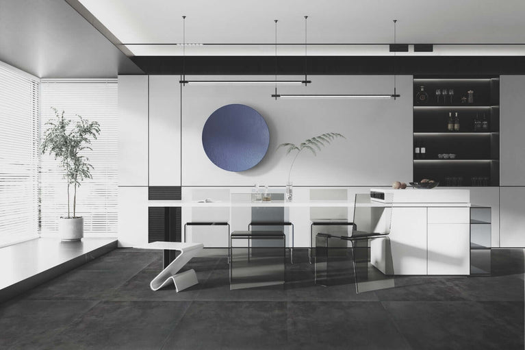 Cuisine moderne minimaliste avec carrelage gris foncé, meubles blancs, grande table en verre, chaises design, et décoration murale circulaire bleue, créant une ambiance épurée et élégante.