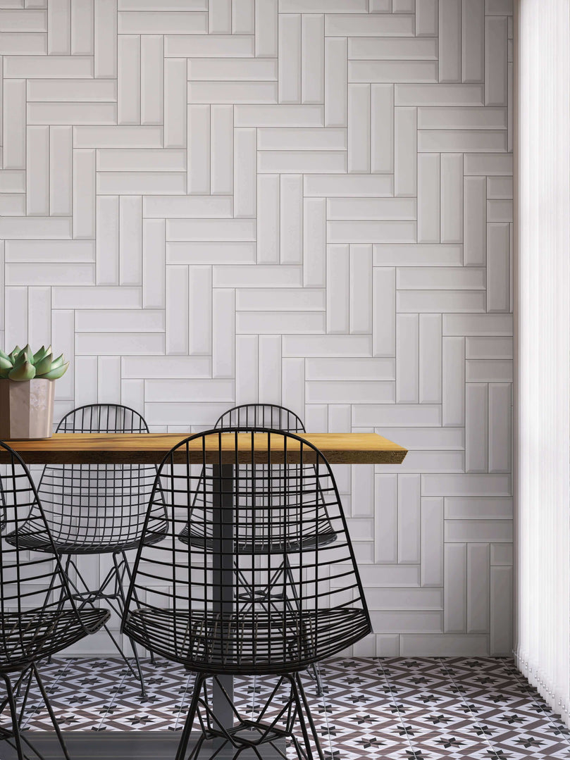 Carreaux de métro blancs en céramique disposés en motif chevron sur un mur de cuisine moderne, avec table en bois et chaises en métal noir, créant un contraste élégant et un design contemporain