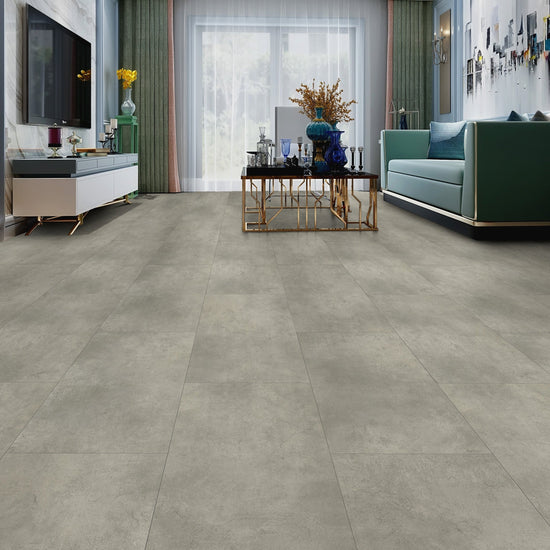 Salon moderne avec plancher en vinyle SPC gris béton, meuble TV blanc, canapé vert, table basse dorée et plantes décoratives, illustrant l'aspect esthétique du revêtement de sol Vinyle SPC Béton Gris Moyen