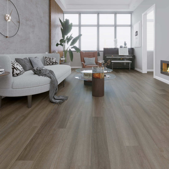 Salon moderne avec plancher en vinyle SPC chêne gris, canapé gris, table basse ronde, grande fenêtre et piano, illustrant l'élégance et la polyvalence du réducteur à usages multiples pour une transition harmonieuse entre les revêtements.