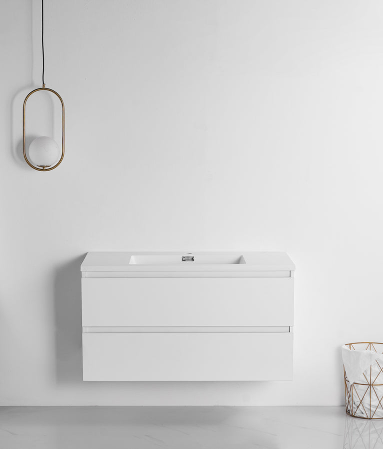 Meuble-lavabo moderne blanc satiné de 40 pouces, suspendu avec deux tiroirs, comptoir en micro cristal mat et lavabo intégré. Luminaire ovale doré suspendu à gauche. Style scandinave minimaliste pour salle de bain contemporaine.