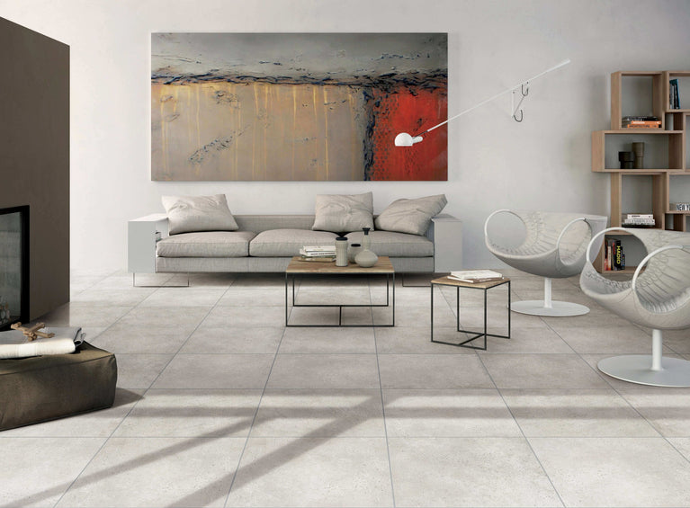 Salon moderne avec carrelage Céramique Stone Cement Grège au sol, canapé gris, tableau abstrait et mobilier contemporain, illustrant l'élégance et la polyvalence du carrelage pour sols et murs dans un espace résidentiel