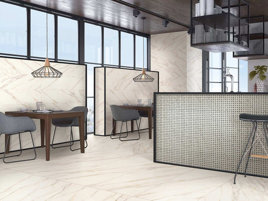 Intérieur élégant avec carrelage Céramique Marble Stone Oro 24"x48" au sol et murs, cuisine ouverte avec îlot, espace repas avec tables en bois et chaises grises, luminaires suspendus géométriques, grandes fenêtres offrant beaucoup de lumière naturelle
