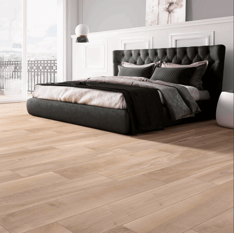 Chambre moderne avec lit noir luxueux sur un sol en céramique imitation bois chêne clair, illustrant l'élégance et la durabilité du carrelage Céramique Wood K Chêne dans un espace résidentiel.