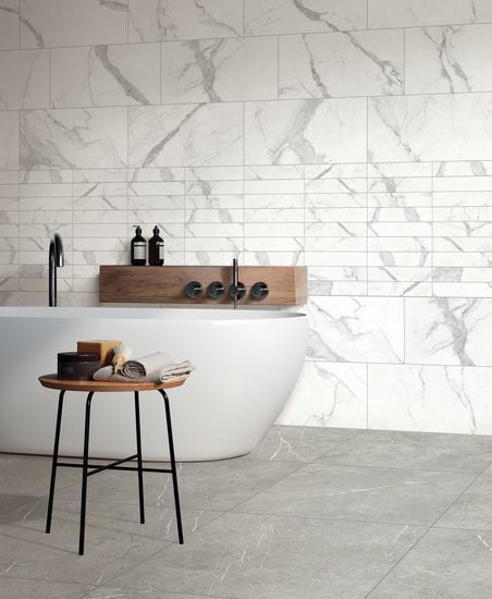 Salle de bain élégante avec carrelage en marbre Grigio, baignoire autoportante blanche, table d'appoint en bois et mur en céramique effet pierre marbrée 24"x48