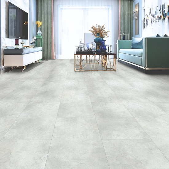 Salon moderne avec sol en vinyle SPC gris pâle, meuble TV, canapé bleu, table basse dorée et décoration élégante, illustrant l'utilisation polyvalente du réducteur pour une transition harmonieuse entre les revêtements.