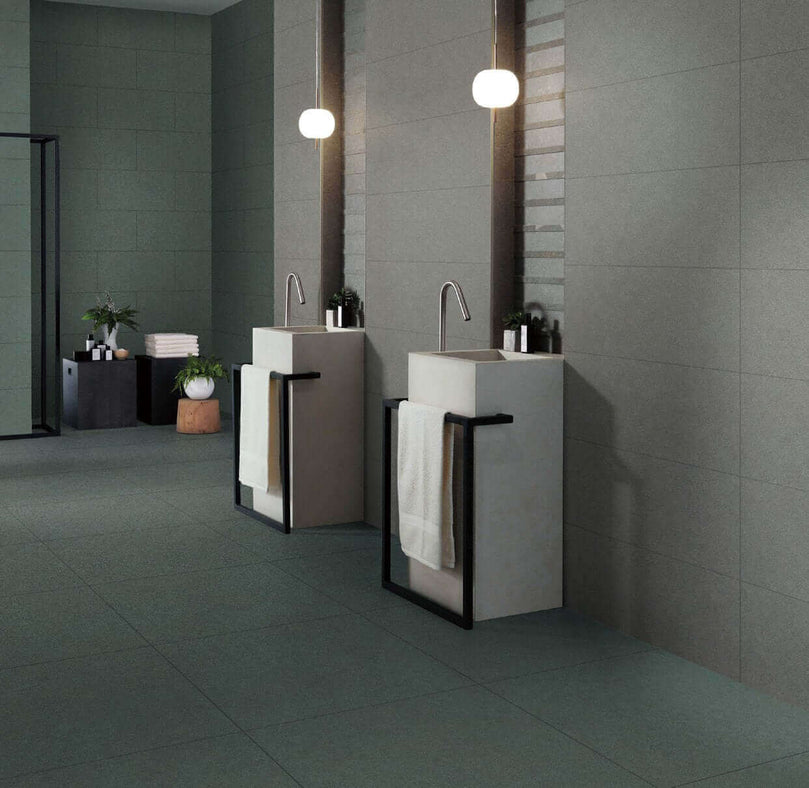 Salle de bains moderne avec carrelage gris Céramique Classique Grigio, lavabos sur pied élégants, miroirs suspendus et éclairage minimaliste. Ambiance épurée et sophistiquée pour un espace résidentiel ou commercial léger.