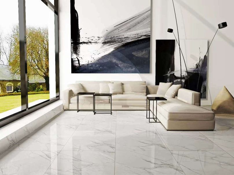 Salon moderne avec carrelage Céramique Calacatta Cielo White Polie, canapé blanc, grande fenêtre et œuvre d'art abstraite. Sol en céramique blanc brillant reflétant la lumière naturelle, créant une atmosphère lumineuse et spacieuse.