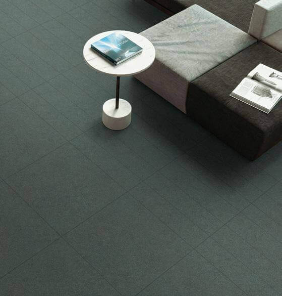 Salon moderne avec céramique effet pierre au sol, mobilier minimaliste et ambiance lumineuse, mettant en valeur la texture naturelle de la céramique.