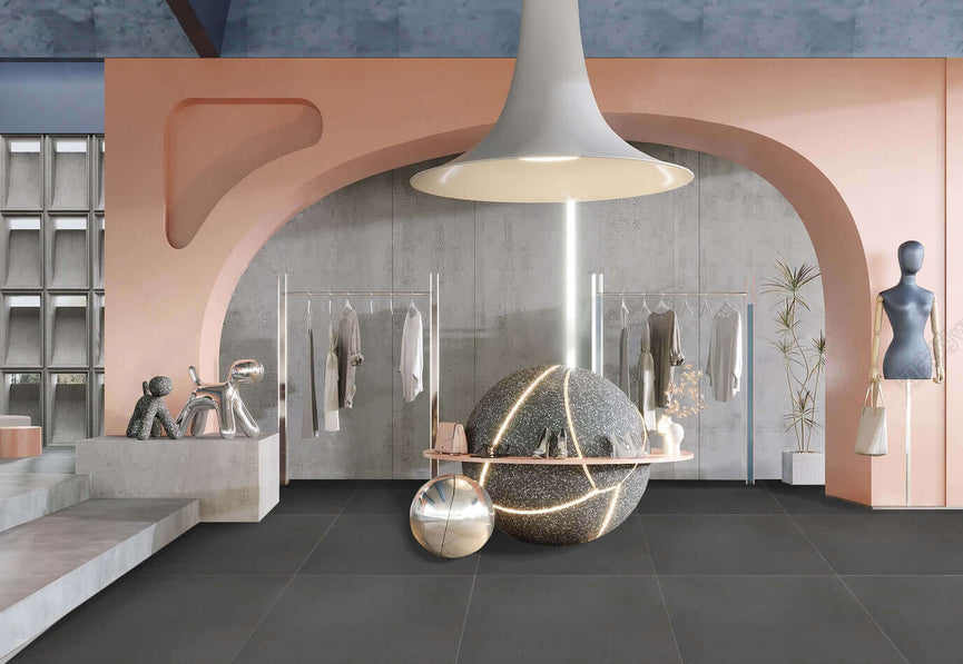 Intérieur moderne avec carrelage Céramique Plain Carbon au sol, murs roses et gris, grande arche, luminaire suspendu et décorations sphériques. Espace boutique élégant et minimaliste.