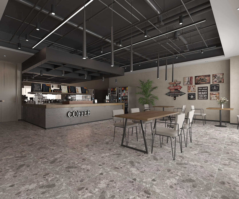 Intérieur de café moderne avec sol en carrelage gris Céramique Dolce di Grès Carbon, comptoir de café, table en bois, chaises métalliques, plafond industriel et décorations murales éclectiques.