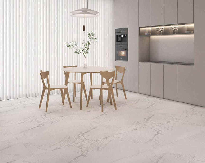 Cuisine moderne avec carrelage Céramique Wow Calacatta 24"x48" Lappato au sol, table ronde en bois clair, chaises assorties, armoires blanches et électroménagers intégrés, créant une ambiance élégante et lumineuse