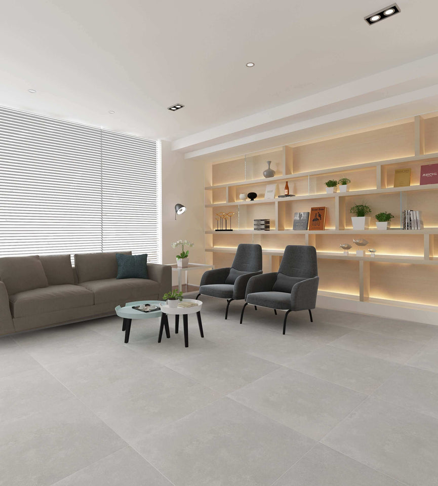 Salon moderne avec les carreaux Céramique Betonia Blanc, comprenant un sofa, des fauteuils, des étagères intégrées et de grandes fenêtres, mettant en valeur la polyvalence du carrelage dans les espaces résidentiels et commerciaux légers.
